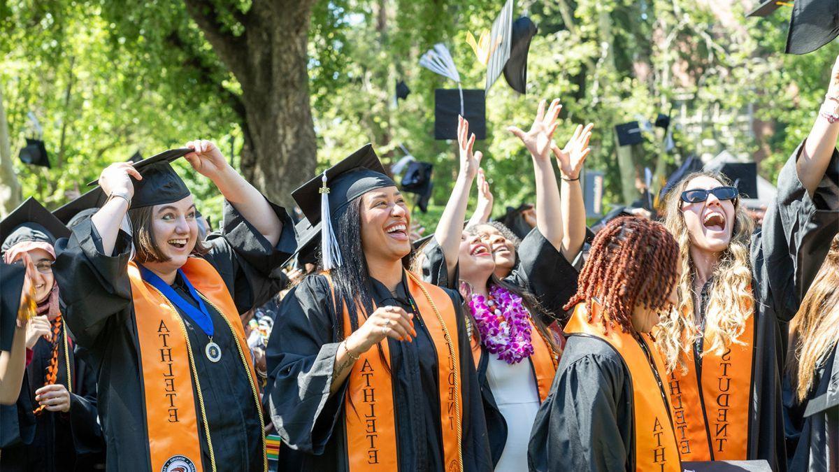 student-athletes throw their graduation caps into the air at commencement