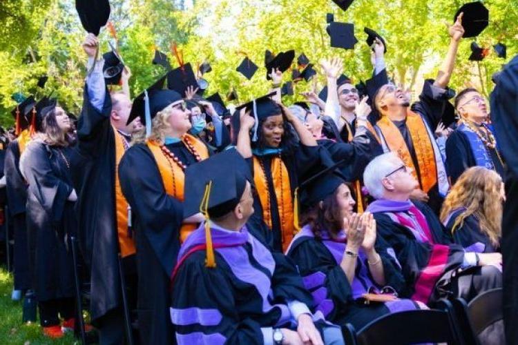 Graduate throw their caps in the air.